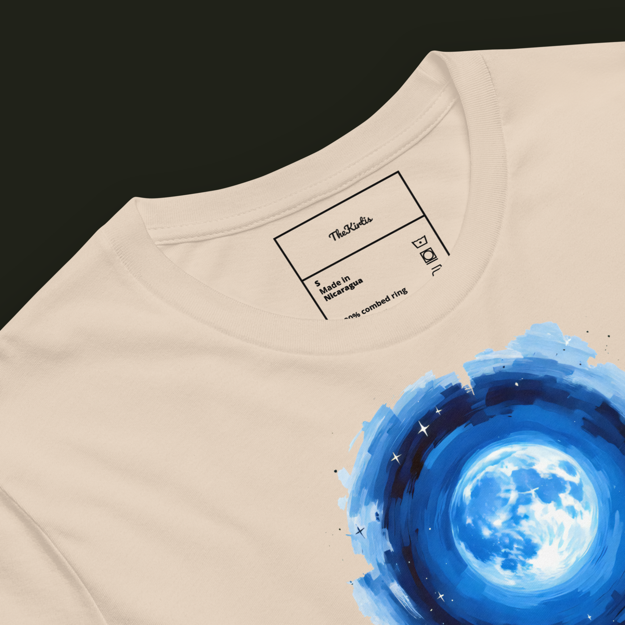 Close-up of the Lunar Tide artwork on a soft cream unisex t-shirt highlighting the luminous blue full moon and surrounding night sky.